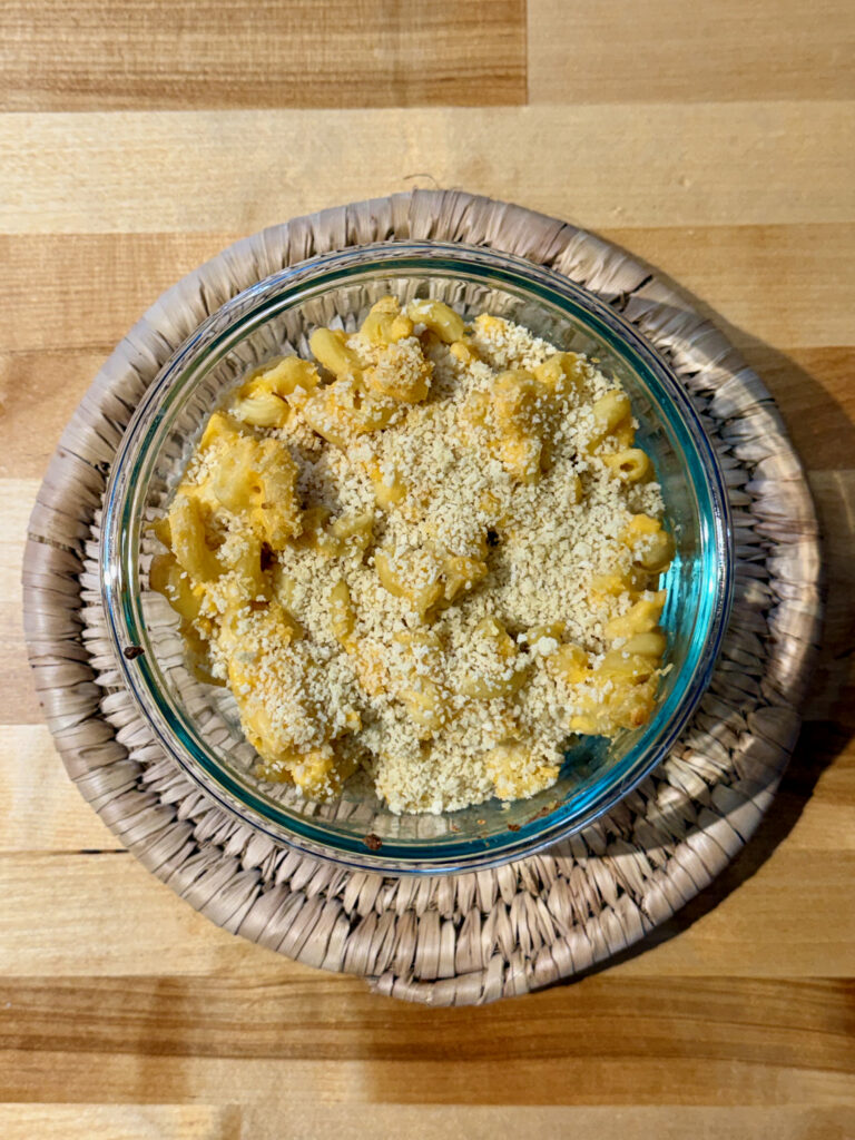 Instant Pot mac and cheese in a glass bowl with toasted panko breadcrumbs on top sitting on trivet