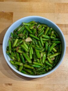 Finished stir fried asparagus in a white bowl