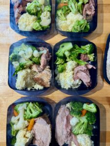 Meal prep containers with left over rice, sliced turkey and fresh vegetables