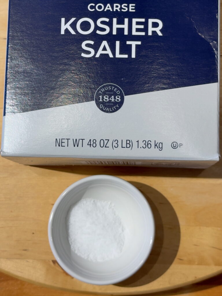 Box of course Kosher salt with a small white dish containing Kosher salt