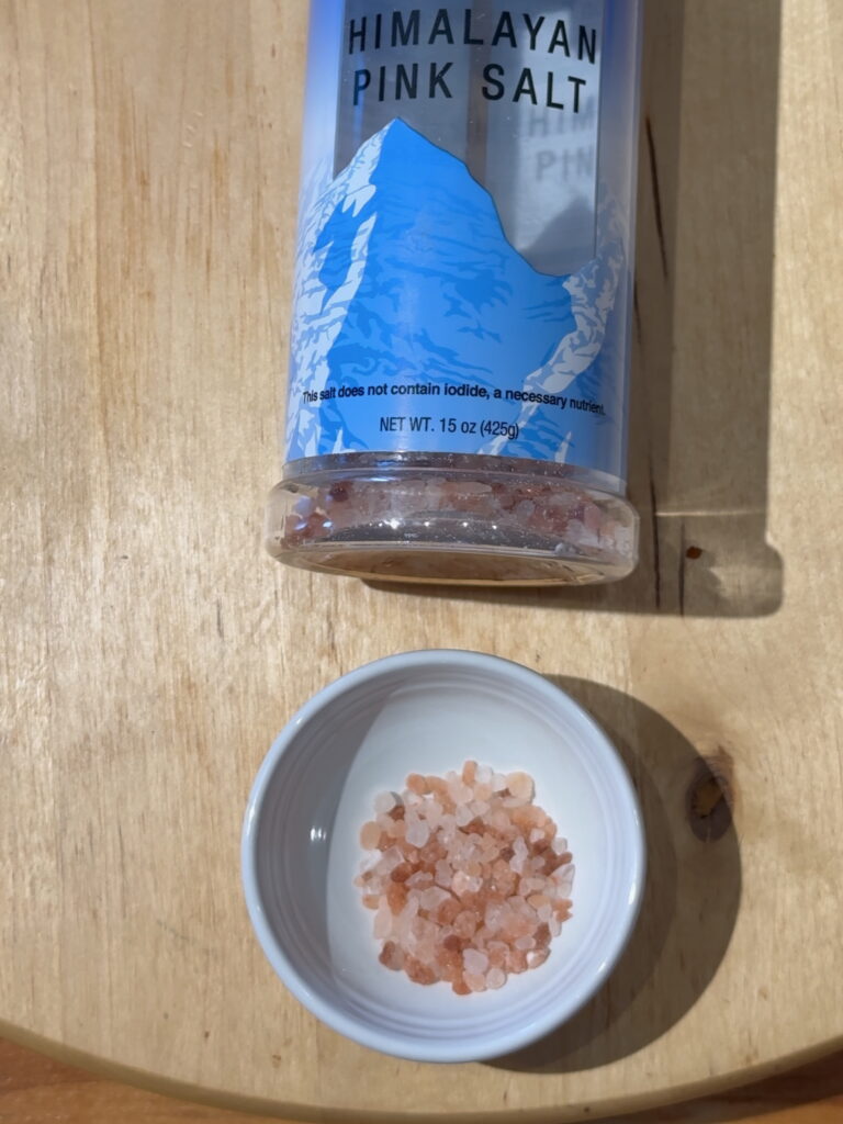Jar of pink Himalayan pink salt with a small white dish containing pink Himalayan pink salt