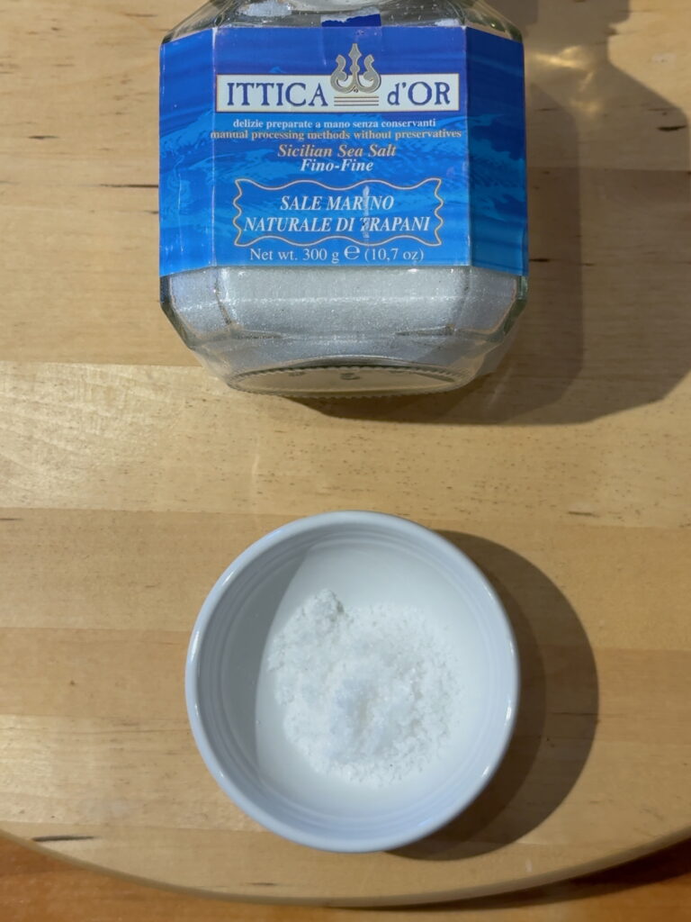 Jar of Ittica d'or sea salt with a small white dish containing the sea salt