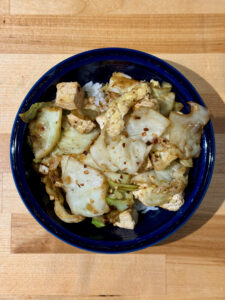 Blue bowl with white rice and the sautéed tofu and cabbage on top