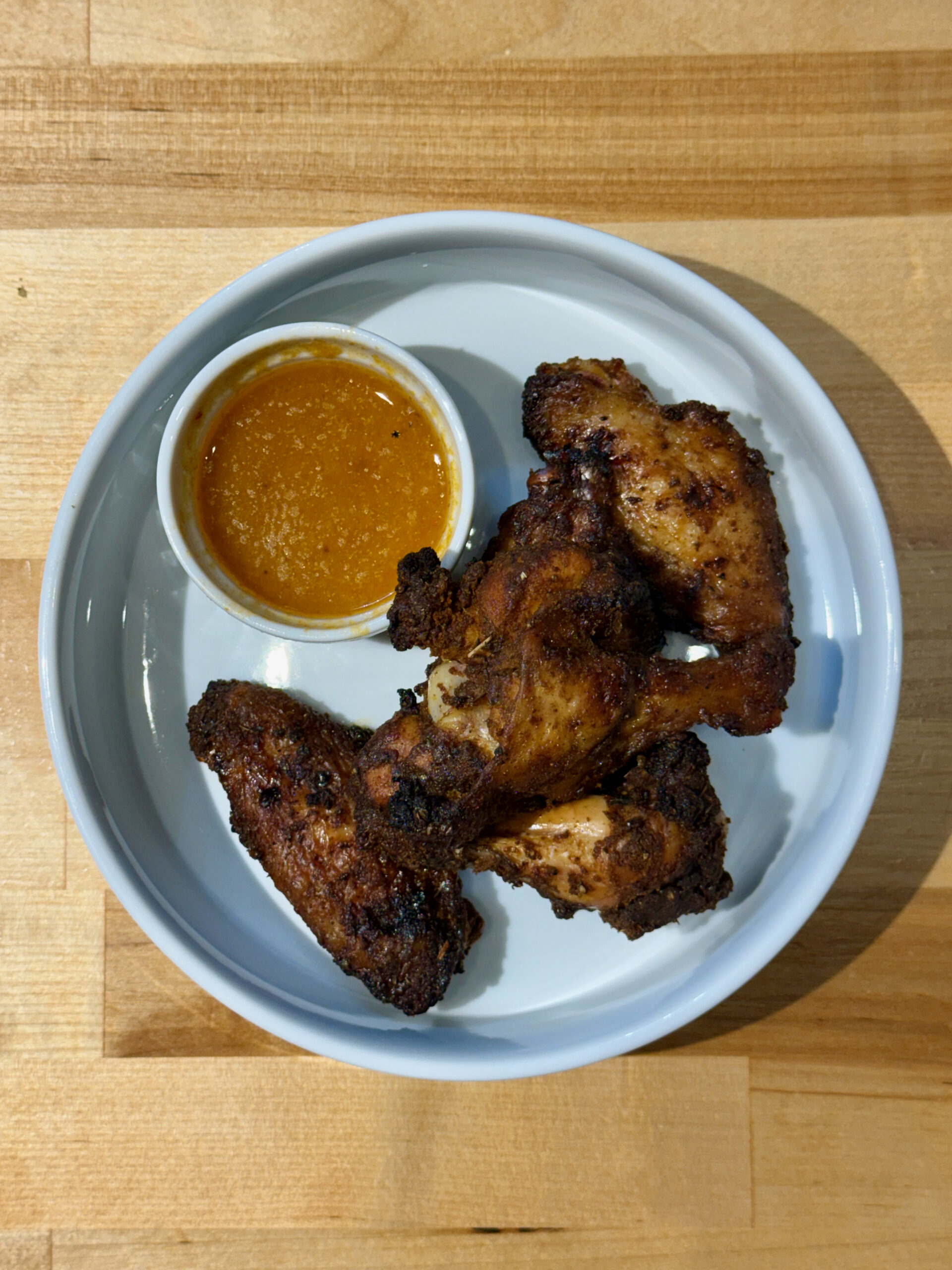 White bowl with five smoked chicken wings with a smaller bowl inside with the wing sauce