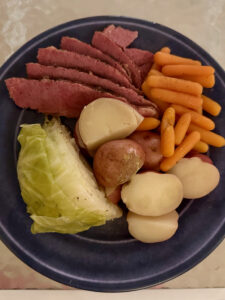 Blue plate with sliced corned beef, steamed cabbage, baby carrots and red potatoes