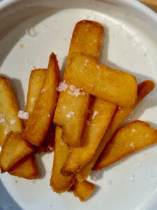 Crispy steak fries with sea salt sprinkled on them in a white bowl