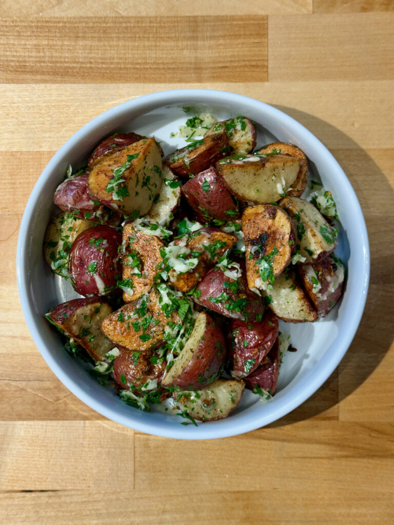 Roasted parmesan red potatoes with parsley in a white bowl