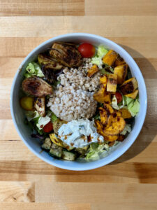 Salad with roasted zucchini, sweet potatoes, butternut squash, pearled barley, Brussels sprouts, tzatziki sauce and balsamic vinegar