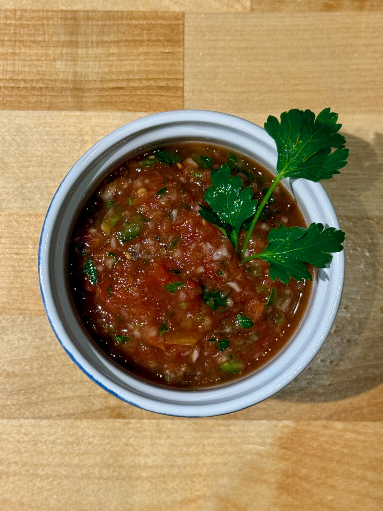 Ramekin filled with low salt salsa finished with a sprig of cilantro leaves