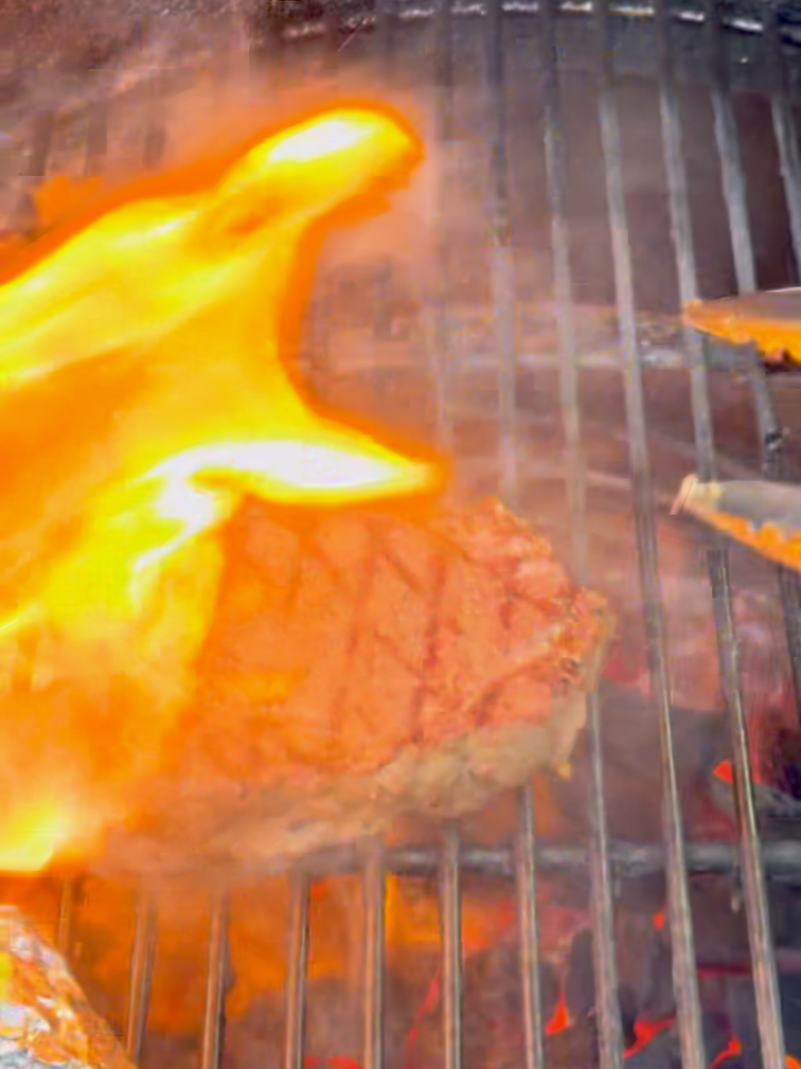Filet Mignon being flipped on the grill with a flame fire-up