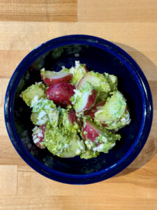 Freshly made Parmesan Pesto Potato Salad in a blue bowl finished with shredded parmesan cheese