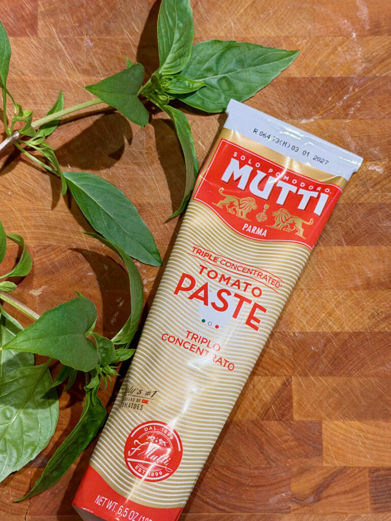 Tube of tomato paste with a sprig of basil